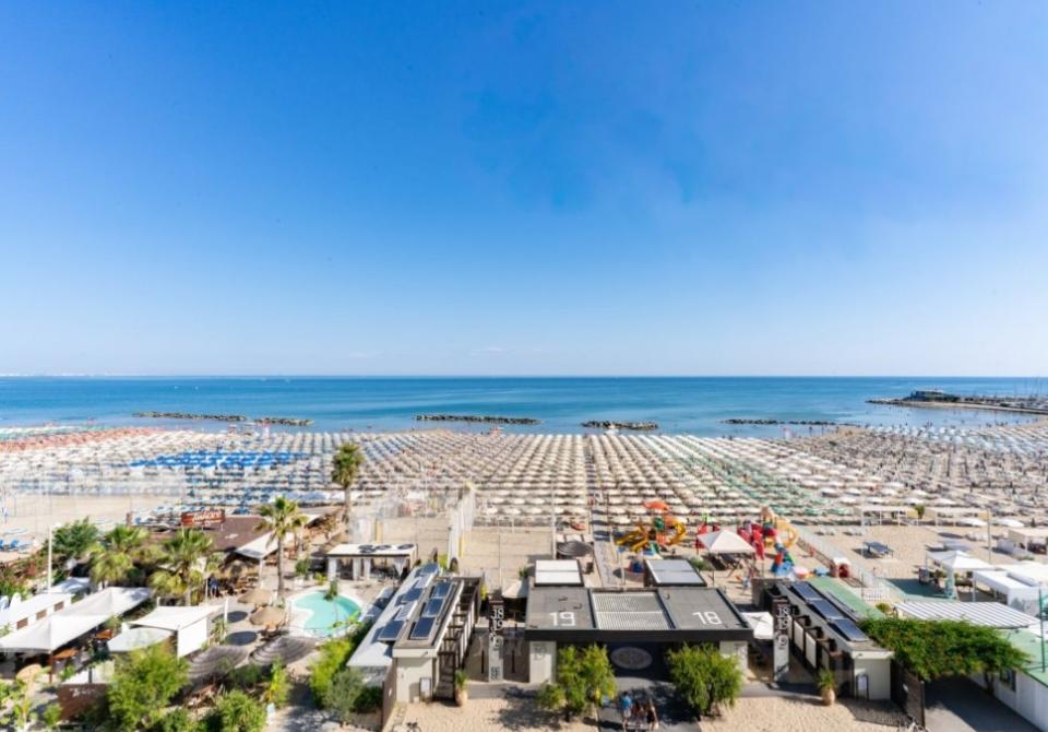 Spiaggia attrezzata con ombrelloni e mare calmo sotto un cielo limpido.