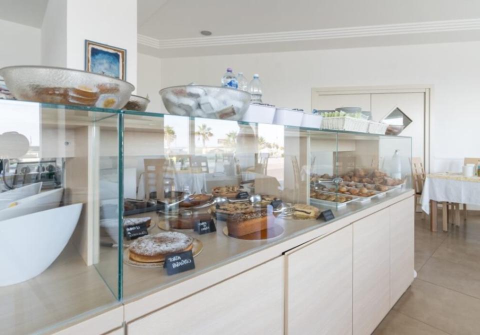 Buffet con dolci assortiti esposti in una vetrina in un ristorante luminoso.